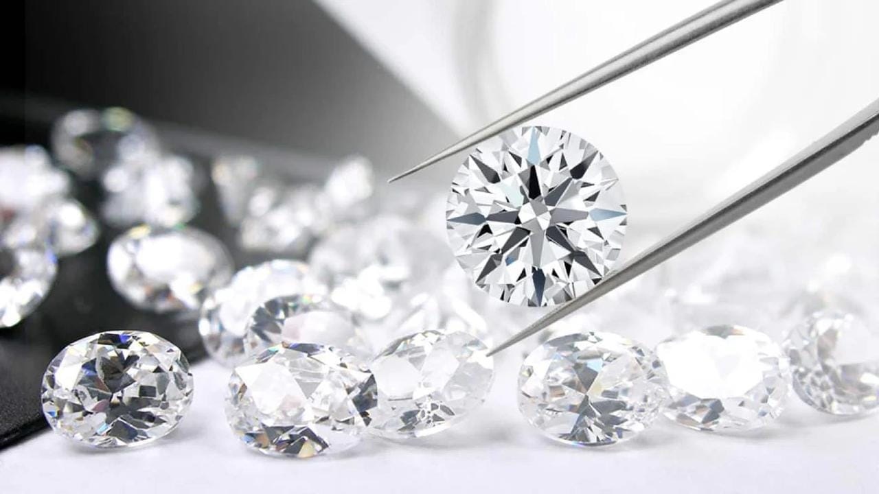 Diamanti naturali tagliati, uno trattenuto da pinzette gemmologiche